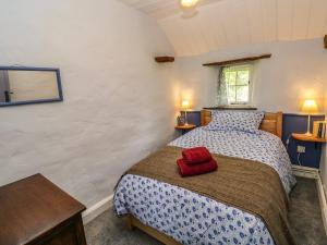 a bedroom with a bed with a red hat on it at Penyrallt Fach Cottage in Llandysul