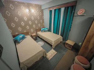 a small room with two beds and a chair at StayCation Homestay in Gangtok