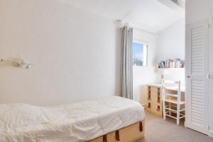 ein weißes Schlafzimmer mit einem Bett und einem Fenster in der Unterkunft Escapade familiale a deux pas de la plage in La Guérinière