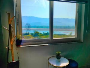 a table and a window with a view of the water at Blue Heart Home by the Ganges - Cosy 1Bhk-Veerbhadra in Rishīkesh