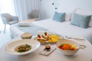 una mesa con un plato de comida y una cama en Neptuno Hotel & SPA 4 Sup, en Calella