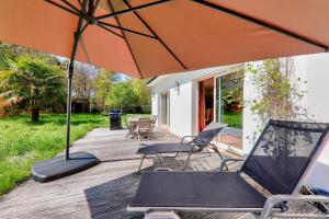 an orange umbrella and chairs on a deck at Carnac - 7 Voyageurs - 100 % Nature in Crach