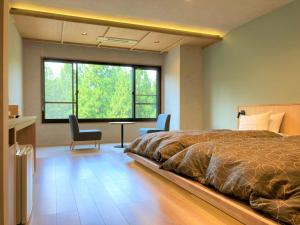 um quarto com uma cama, 2 cadeiras e uma janela em 田沢湖水沢温泉郷セルリアンリゾートAoni em Senboku