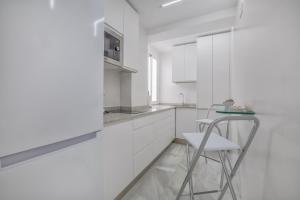 cocina blanca con silla y mesa en Apartamentos Haranas II & Parking, en Córdoba