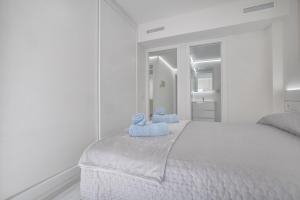 Un dormitorio blanco con una cama con dos animales de peluche azules encima. en Apartamentos Haranas II & Parking, en Córdoba 29 fotos más
