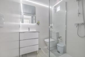 Un baño blanco con inodoro y ducha. en Apartamentos Haranas II & Parking, en Córdoba