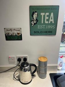 a tea kettle sitting on a counter with a sign on the wall at Wolf Hollow, sleeps 4 adults plus 2 children, Buxton town centre in Buxton