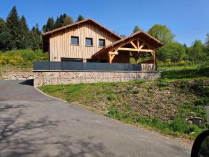 a large wooden house with a stone retaining wall at Gîte du Bambi in Gerbamont 