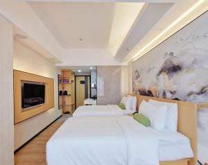 a hotel room with two beds and a tv at Connar Hotel - Shenzhen Shawei in Shenzhen