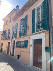 a building with green shutters and a door on a street at Charmante vakantiewoning 'Casa Di Tonno' in Loreto Aprutino
