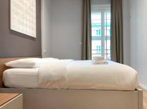 uma cama branca com lençóis brancos e uma janela em Apartment 49 em Trieste