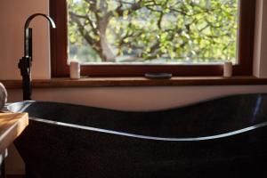 a black bath tub in a bathroom with a window at Életem Art Cabin in Esztergom