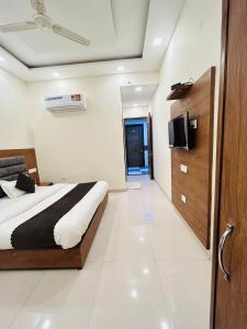 Hotel Wood Lark Zirakpur Chandigarh- A unit of Sidham Group of Hotels في شانديغار: غرفة نوم بسرير وتلفزيون على جدار