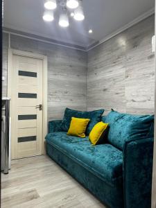 a blue couch with two yellow pillows in a room at Apartment in Chişinău