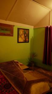 a bedroom with a bed with a picture on the wall at Shoolin Cottages & Camp's in Kasol