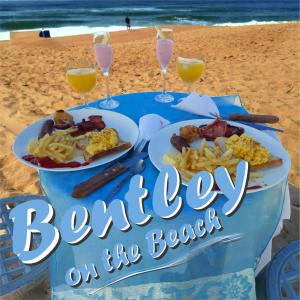 a table with two plates of food on the beach at Bentley on the Beach in Durban