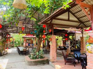 a patio with tables and chairs and a tree at Hue Lotus Homestay in Hue