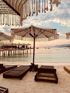 a beach with benches and umbrellas on the sand at Orfeu apartments Ksamil in Ksamil