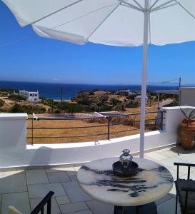 una mesa en un balcón con sombrilla en Peaceful, panoramic seaview retreat, en Moutsoúna