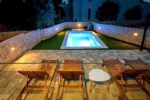 ノヴァリャにあるImperial Apartment with Private Poolの- グループチェア、夜間のスイミングプール