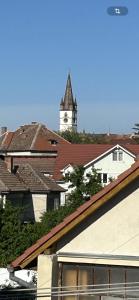 een klokkentoren op de achtergrond van een stad met daken bij Hermann Central Apartment in Sibiu
