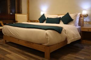 a bedroom with a large bed with green pillows at Guzel Hotel in Shigar