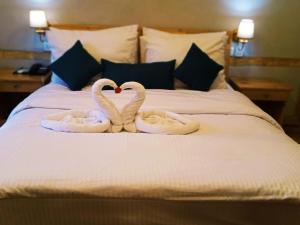 two swansrendered to look like hearts are sitting on a bed at Guzel Hotel in Shigar
