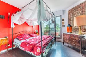 um quarto vermelho com uma cama de dossel e uma cómoda em Appartement avec terrasse a 5 min de Paris em Les Lilas