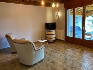ein Wohnzimmer mit einem Sofa, einem TV und einem Tisch in der Unterkunft Maison dans un village viticole in Boyeux-Saint-Jérôme