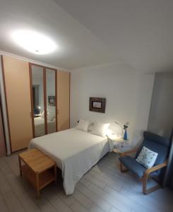ein Schlafzimmer mit einem weißen Bett und einem blauen Stuhl in der Unterkunft Las Canteras, your beach home in Las Palmas de Gran Canaria