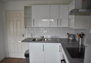 a kitchen with white cabinets and a sink at Chichester Retreat - Quiet City Centre Apartment in Chichester
