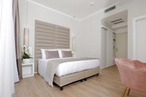 a white bedroom with a large bed and a chair at Hotel Alexander in Milano Marittima