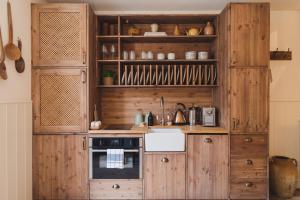 a kitchen with wooden cabinets and an oven at Buckingham Mews_Flint Cottage 2 in Broadstairs
