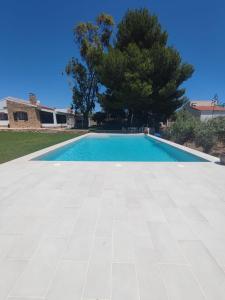 uma piscina com piso em azulejo e uma árvore em Nina´s Paradise em L'Ampolla