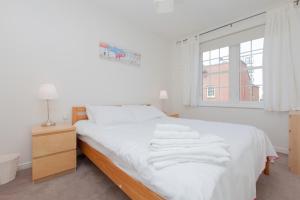 a bedroom with a bed with white sheets and a window at Attractive Edinburgh Leith Apartment in Edinburgh