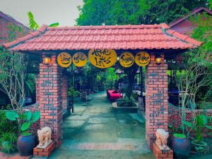 a brick arch with signs on it in a garden at Hue Lotus Homestay in Hue