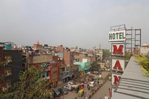 uma cidade com uma placa de hotel e uma rua movimentada em Hotel Mannat at Paschim Vihar em Nova Deli