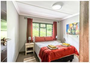 Un dormitorio con una cama con almohadas rojas y una ventana en Lagoon View House, en Knysna