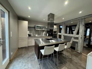 a kitchen with a large island with white chairs at La Maison de l'Ours - Avec Patio & Garage - 8 personnes in Dambach-la-Ville