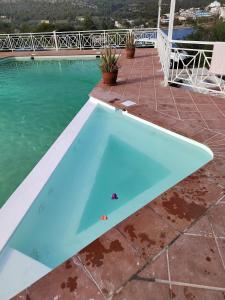 a blue swimming pool on a patio next to the water at Oneiro glico in Agia Marina Aegina