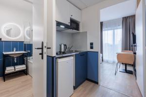 uma cozinha com armários azuis e brancos e um lavatório em Résidence Du Parc Val d'Europe em Montévrain