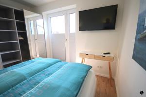 1 dormitorio con 1 cama y TV en la pared en Kapitänshaus 2, en Kellenhusen