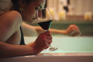 a woman is holding a glass of wine at La Suite SPA privatif du Moulin in Saint-Laurent-dʼAndenay