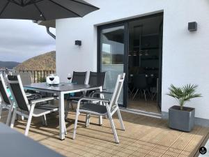 a dining table and chairs on a deck with an umbrella at Haus Sonnendeck - Sonnenweg 21 in Heringhausen