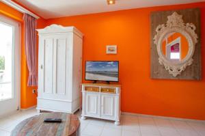 ein Wohnzimmer mit orangefarbenen Wänden und einem TV auf dem Tisch in der Unterkunft Emil - Sonnenhof 1 in Kellenhusen