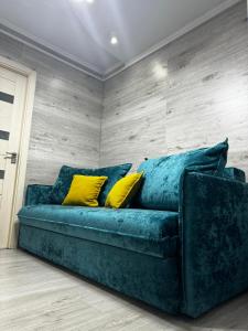 ein blaues Sofa mit gelben Kissen in einem Zimmer in der Unterkunft Чем дольше тем дешевлe in Chişinău