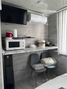 eine Küche mit 2 Stühlen und einer Theke mit einer Mikrowelle in der Unterkunft Чем дольше тем дешевлe in Chişinău