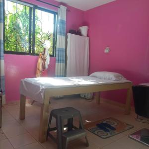 a room with a table and a pink wall at Zaradise Suites in Mombasa
