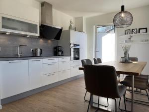 cocina con armarios blancos y mesa de madera en Diemelblick 12 - LENI, en Heringhausen