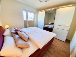 una camera da letto con letto, lenzuola e cuscini bianchi di Kapitänshaus 3 a Kellenhusen